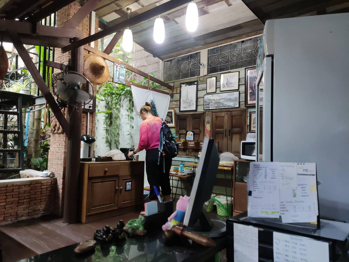 Breakfast corner inside the wooden house at Tamarind Guesthouse, brick wall hung with old Ayutthaya photographs