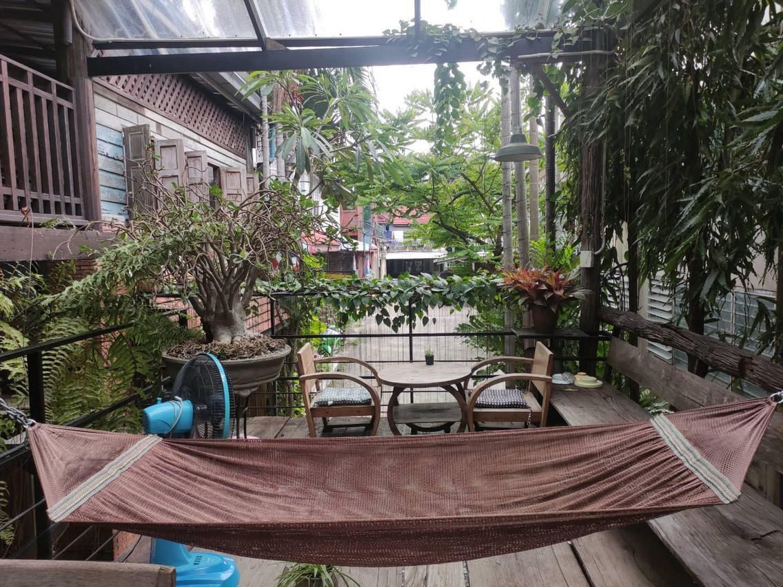 Shared wooden terrace with bonsai, a hammock and a wooden table at Tamarind Guesthouse