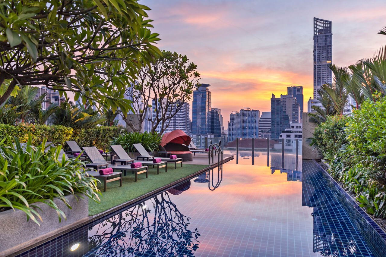 Rooftop pool at Aloft Bangkok Sukhumvit 11 with the city skyline at dusk