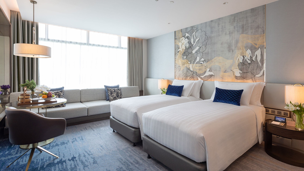 Deluxe room at Chatrium Grand Bangkok in blue-grey tones with gold lotus artwork above the bed
