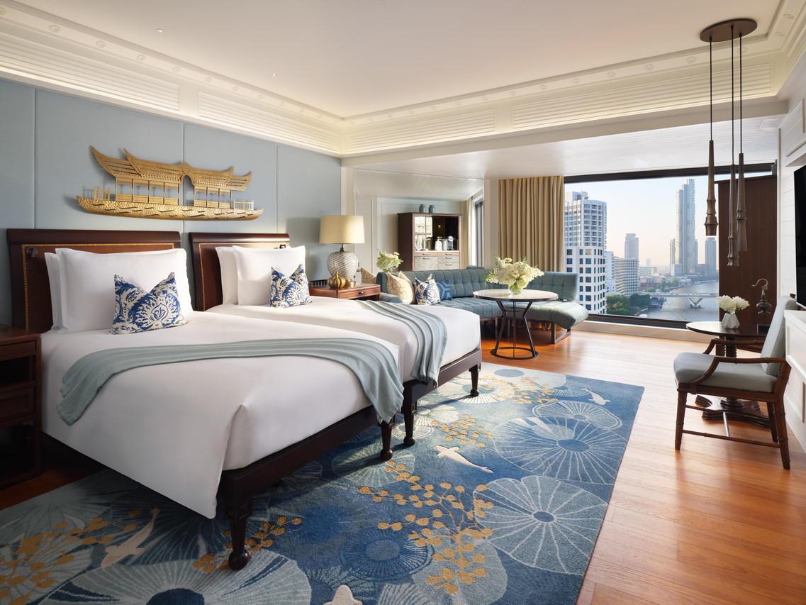 River-view guest room with a royal-barge headboard looking out over the Bangkok skyline