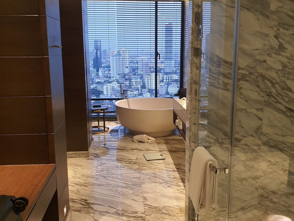 Marble bathroom with round soaking tub and Bangkok skyline view in a 137 Pillars Suites Bangkok suite