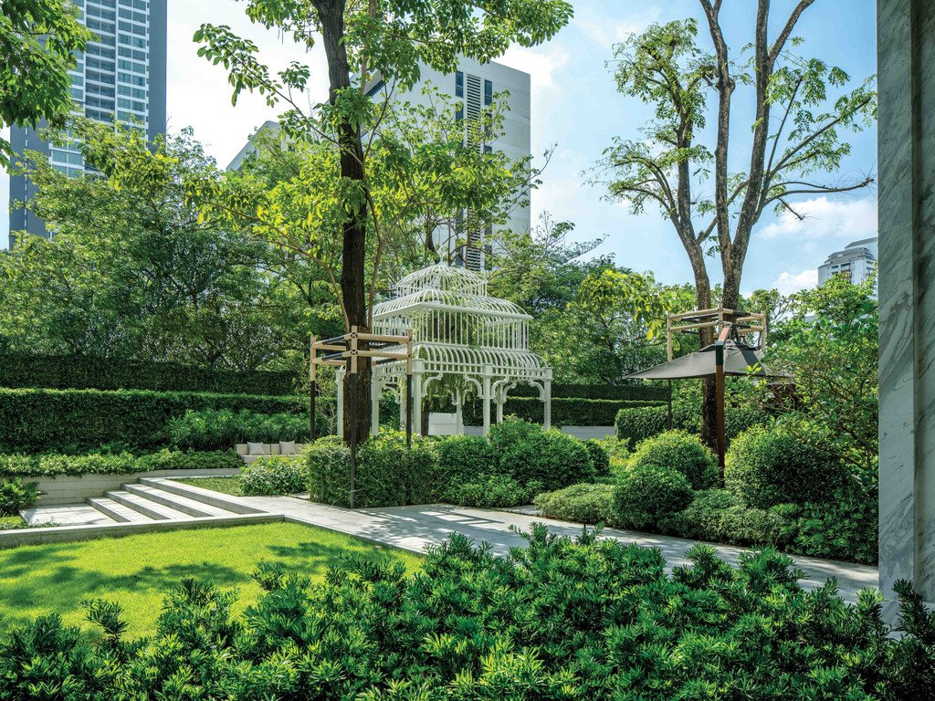 Outdoor garden with white birdcage gazebo and Sukhumvit skyline behind