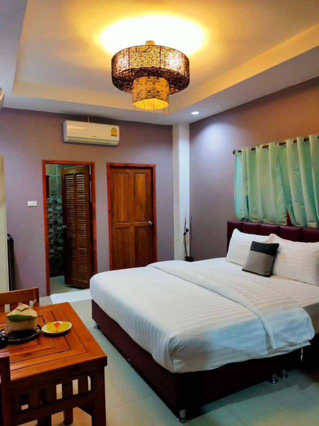 ห้องพักเตียงใหญ่ของ M Grand Hotel พื้นกระเบื้อง มีแอร์ โคมไฟสาน และมุมโต๊ะนั่งเล่น
