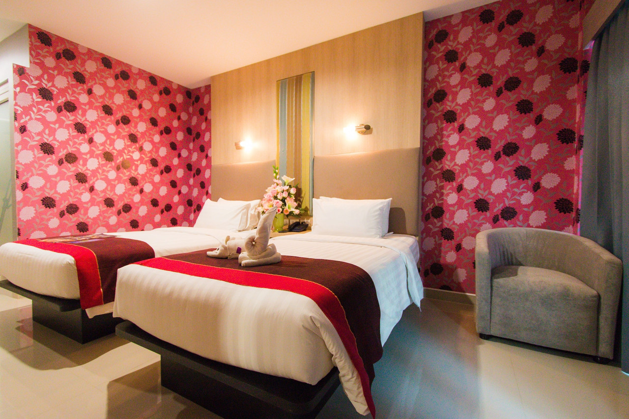 Twin-bed guest room with floral feature wall and bright tiled floor