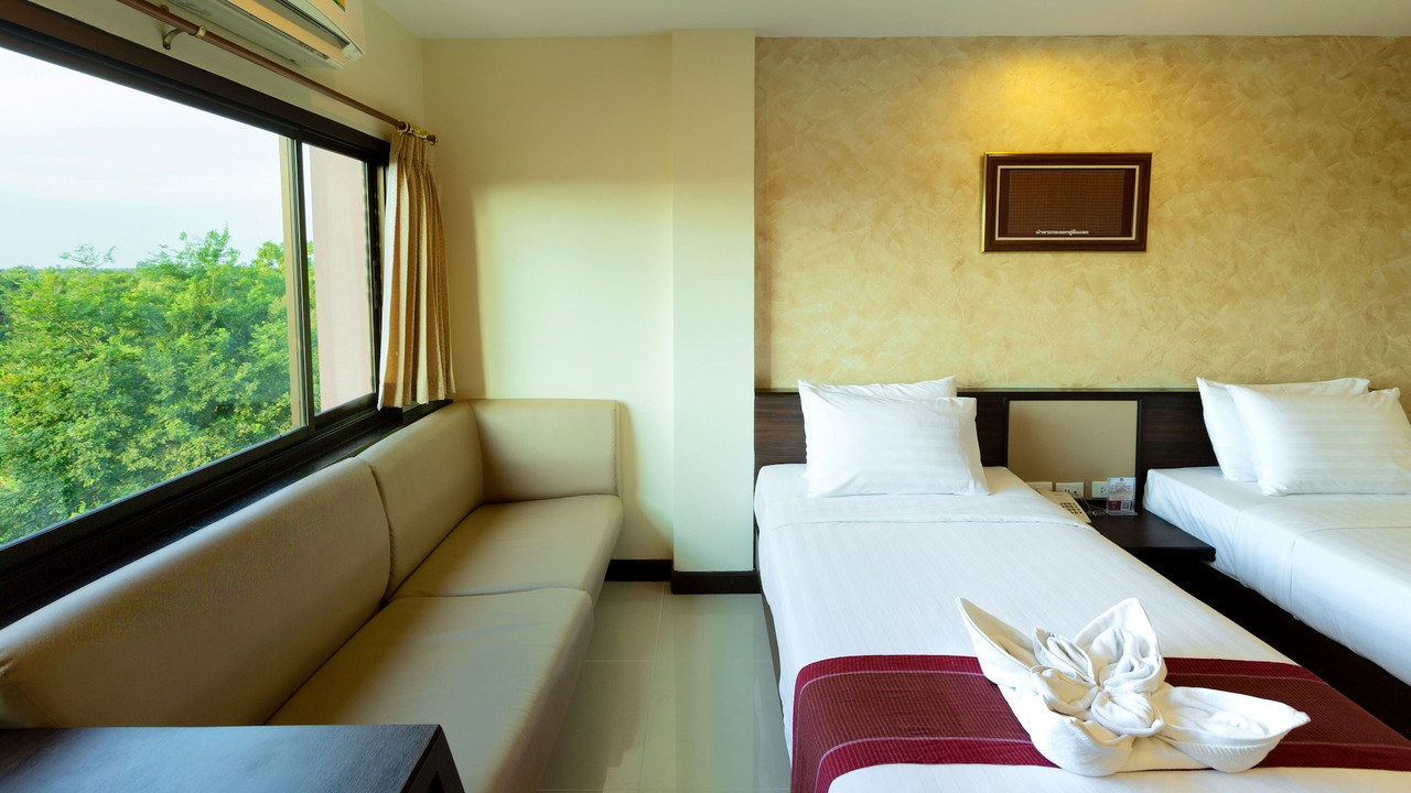 Warm-toned guest room with a window-side sofa overlooking the garden at Phanomrungpuri Hotel