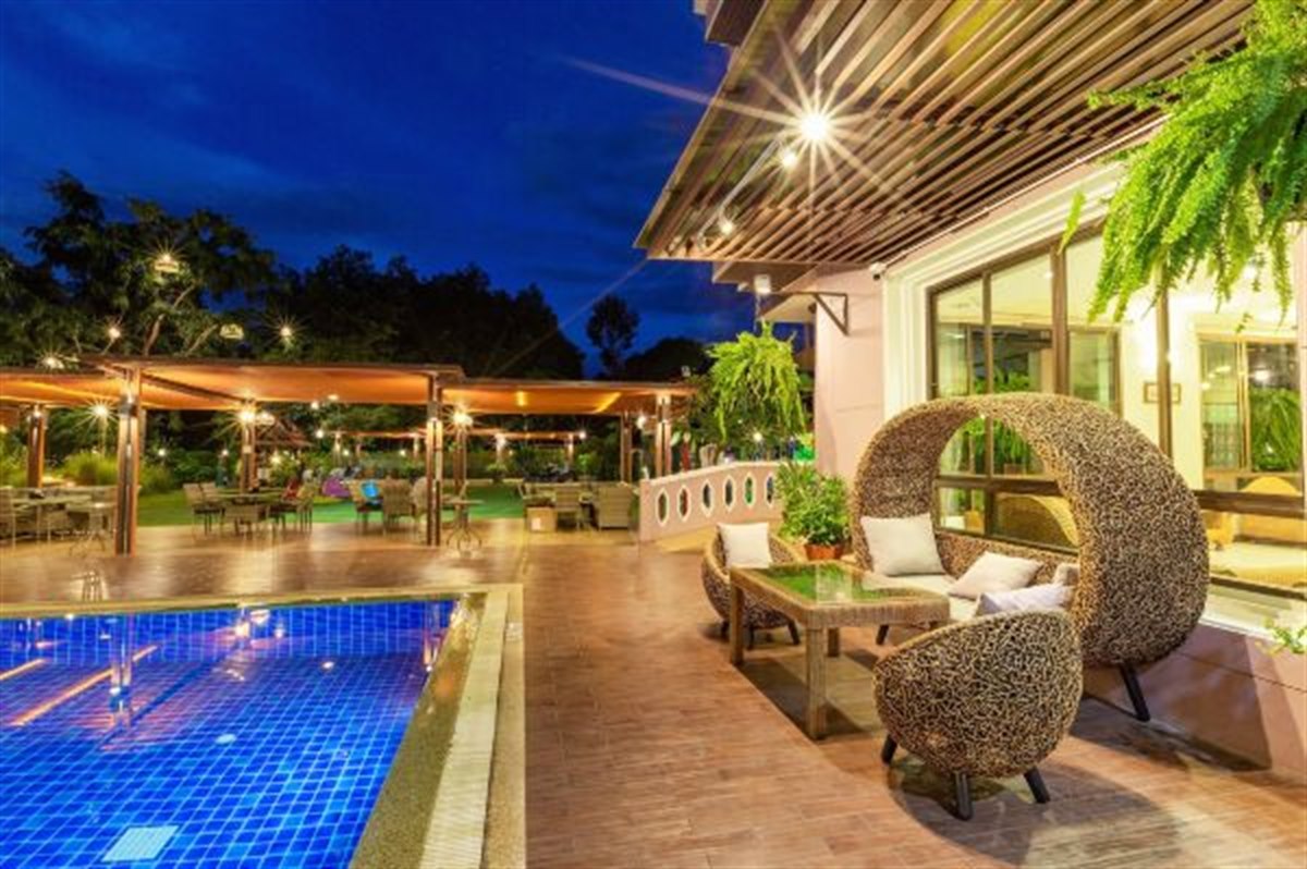 Garden pool at dusk with rattan loungers and a sala pavilion
