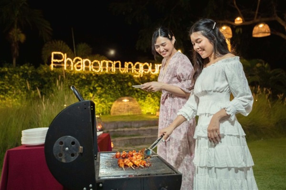 Evening garden corner with the illuminated hotel sign and a barbecue area