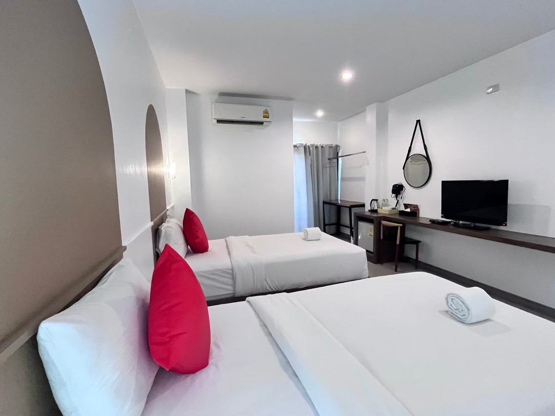 Twin-bed room in white tones with red accent cushions and a work desk at The S Design Hotel