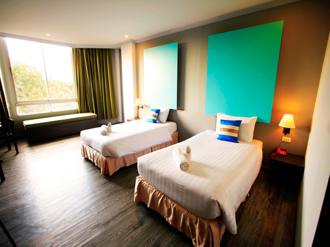 Bright twin room with mint-green wall panels and wood-look flooring
