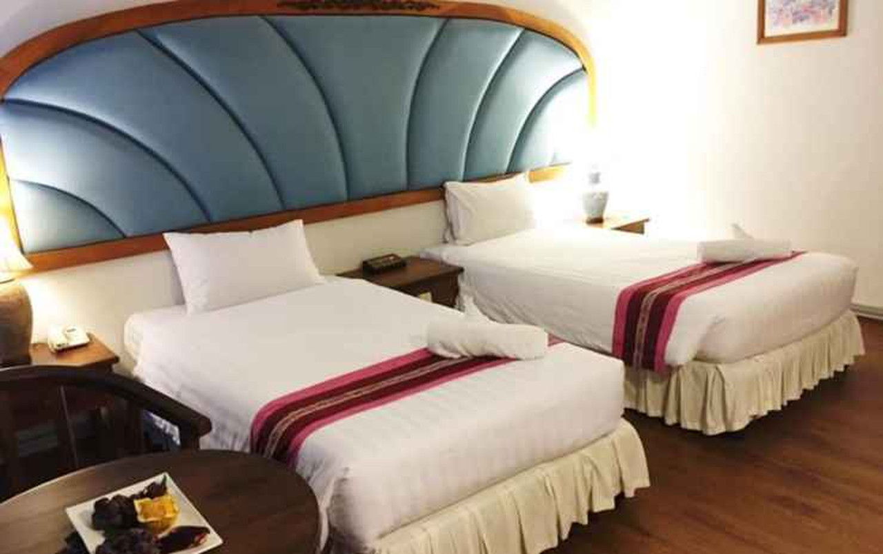 Twin room with a fan-shaped padded blue headboard in an older hotel style