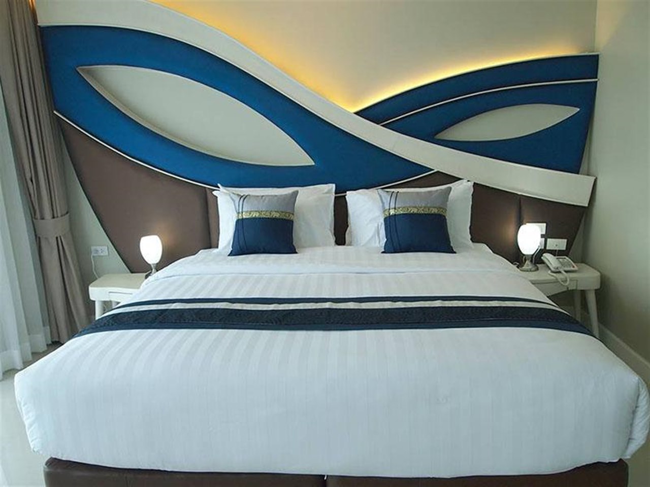 Guest room at Sunrise Lagoon Hotel and Golf with blue curved headboard