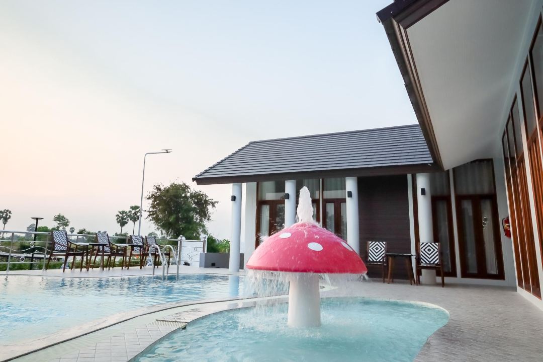 Outdoor pool with a children's mushroom fountain and rice-field views