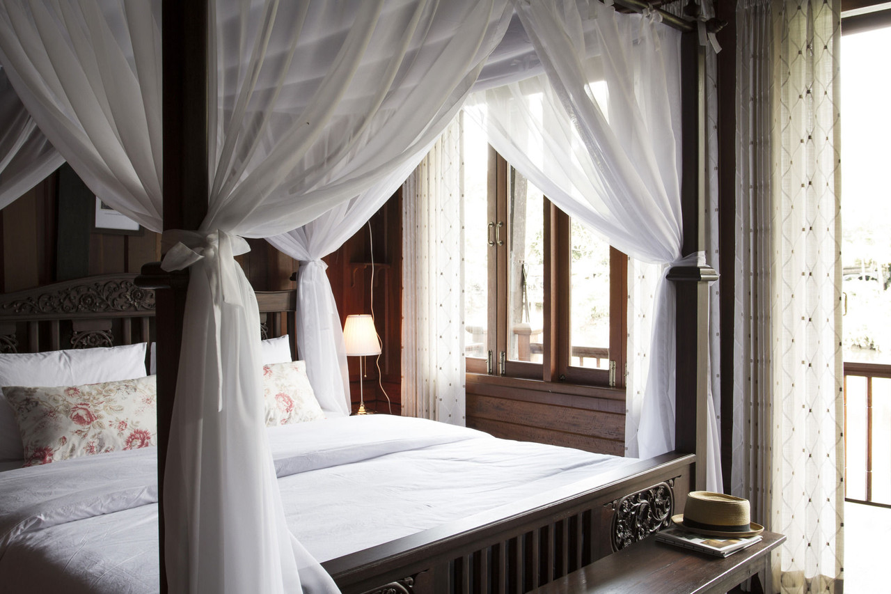 Guestroom with a four-poster bed, sheer mosquito netting and old teak floors