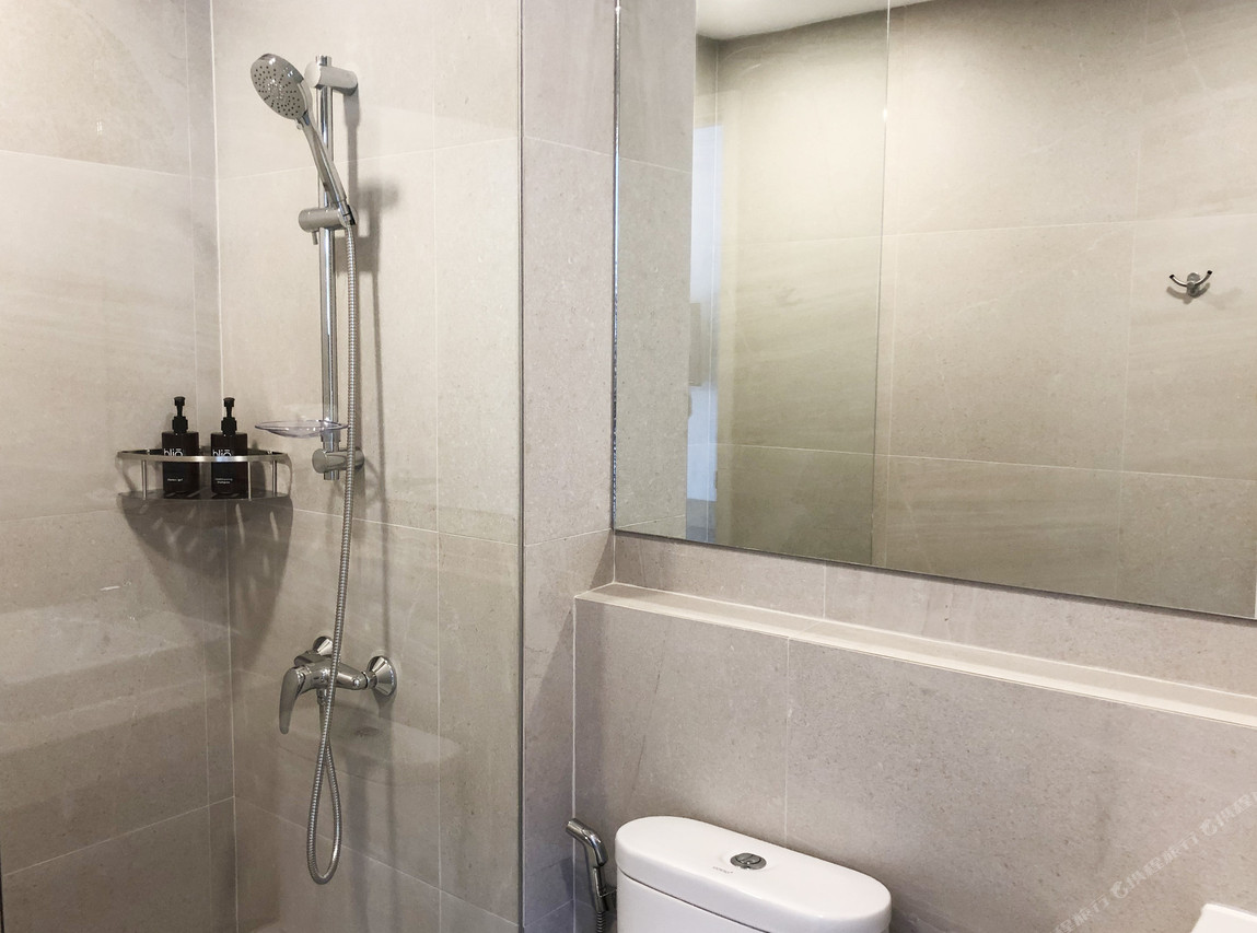 Grey stone-tiled bathroom with rain shower and bliQ-branded toiletries