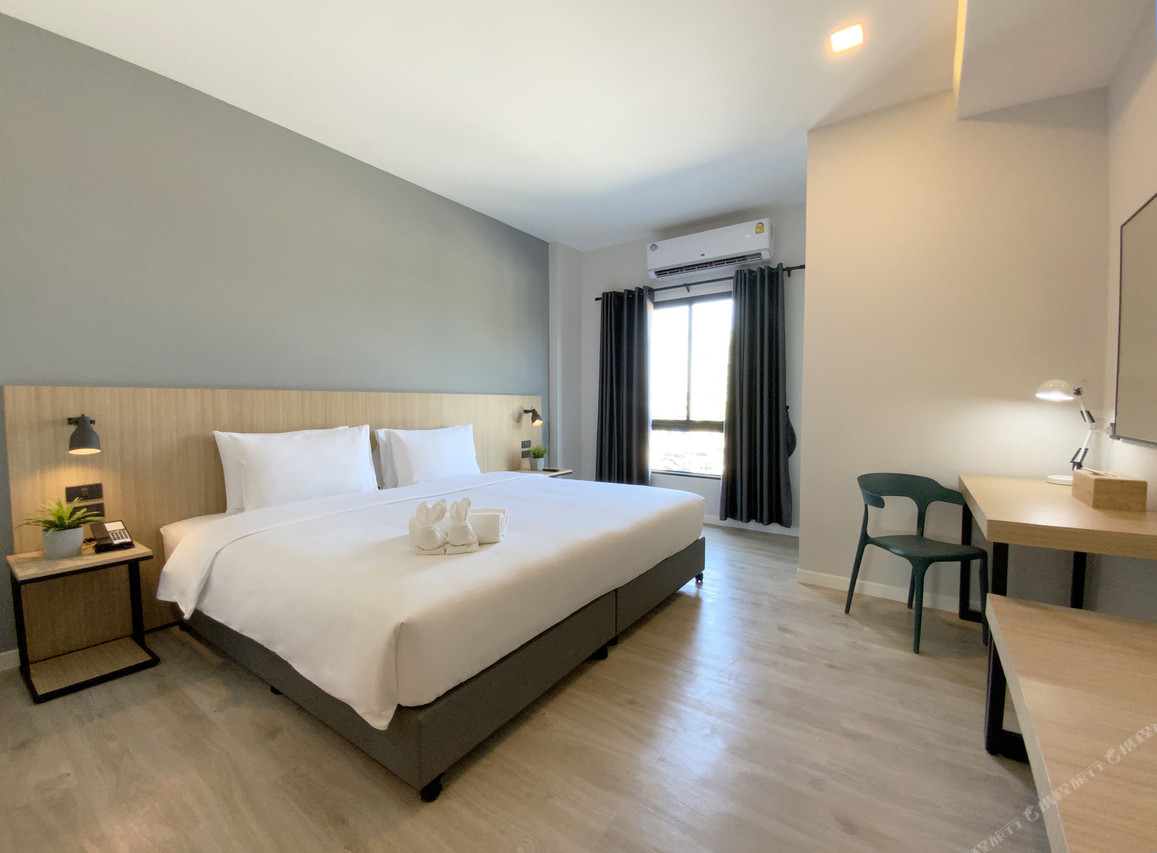 Minimalist bedroom with king bed, sage accent wall, wood floor and desk
