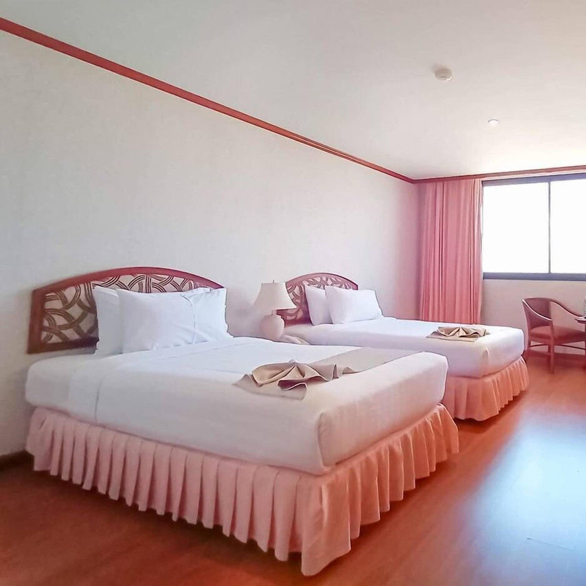 Twin-bed room at K.P. Grand Hotel with wood furniture, wood floor and peach curtains