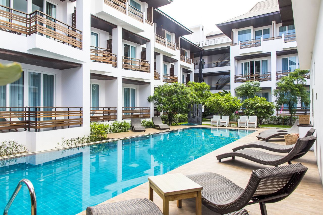 Outdoor saltwater pool set mid-building with sun loungers alongside