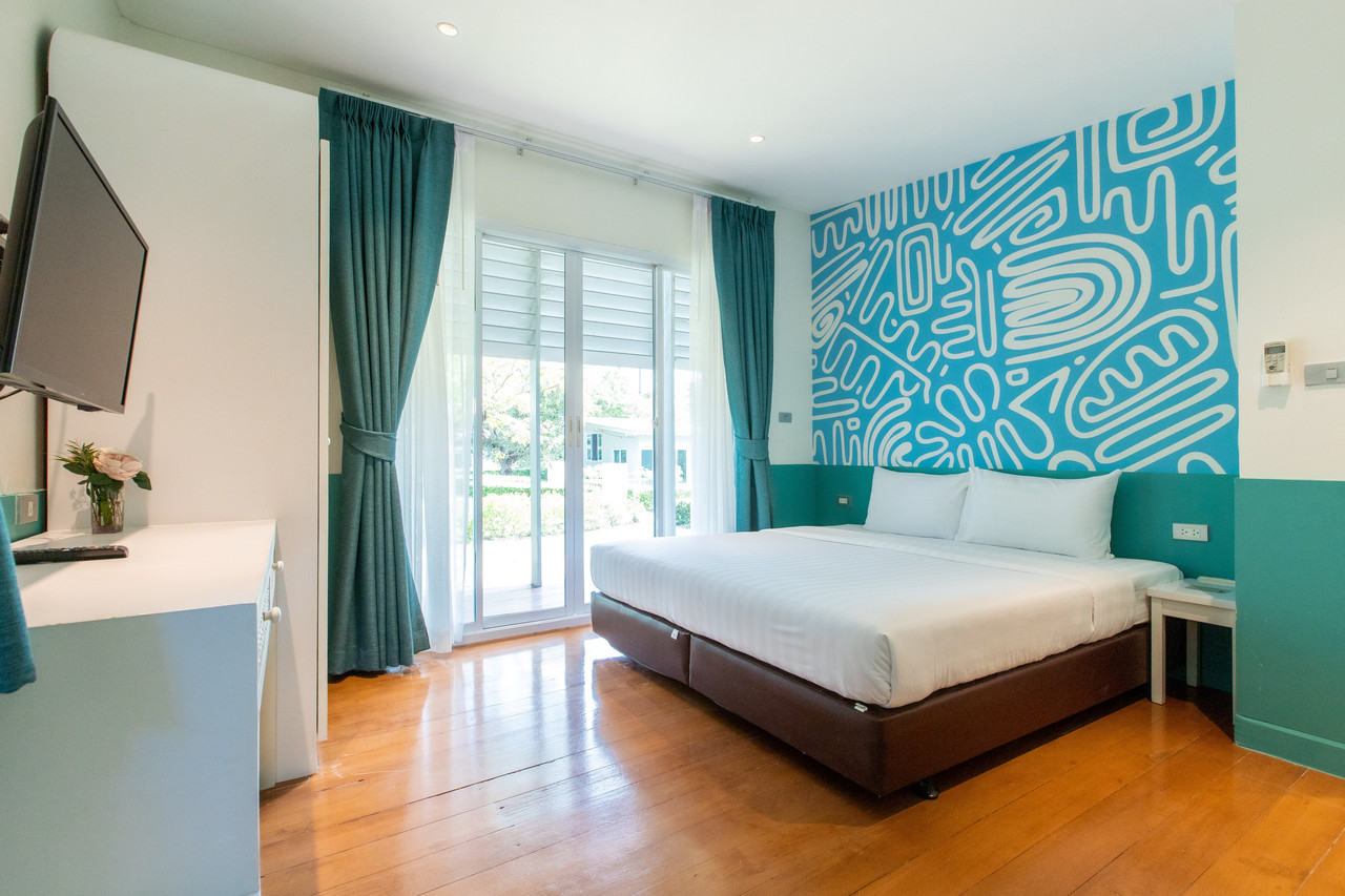 Mint-green guest room with private balcony and garden view at Bangsaen Heritage Hotel
