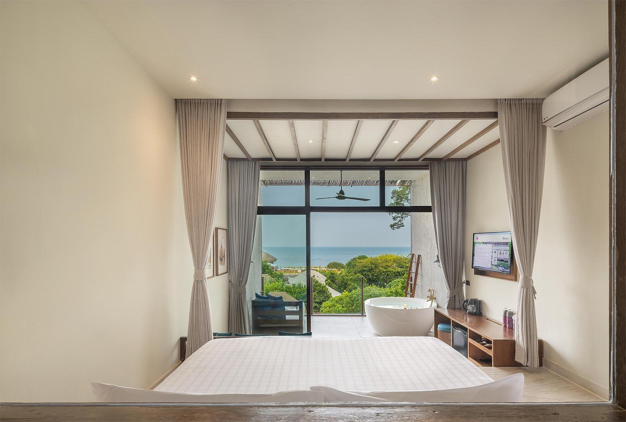 Sea-view room with freestanding tub and floor-to-ceiling windows over the bay