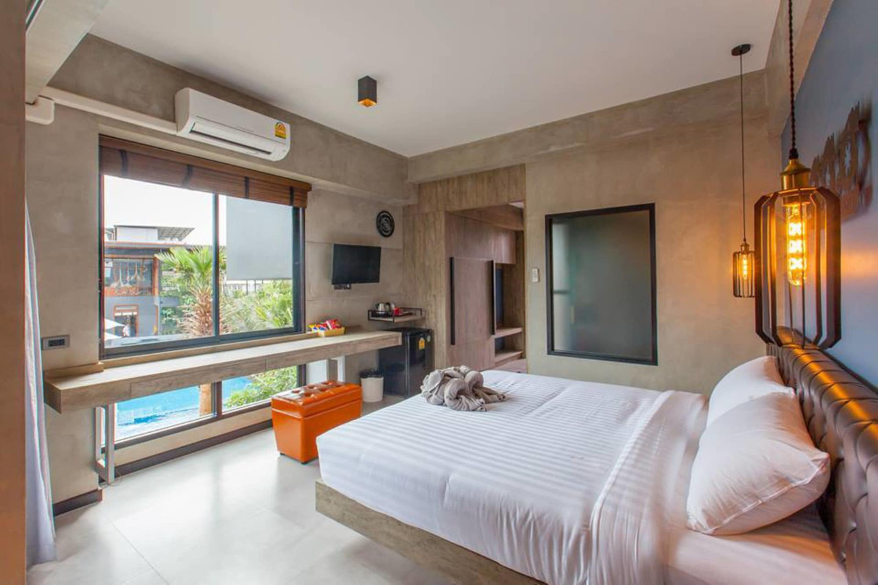 ห้องพัก Loft Mania ผนังปูนเปลือย หัวเตียงหนัง ไฟ Edison วิวสระ