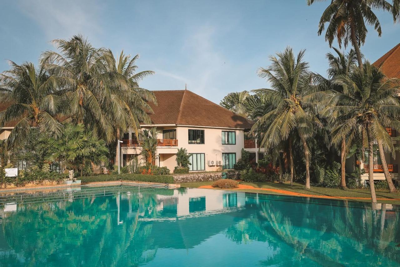 สระว่ายน้ำกลางแจ้งของ The Nouveau Chumphon กับอาคารรีสอร์ตและแนวมะพร้าว