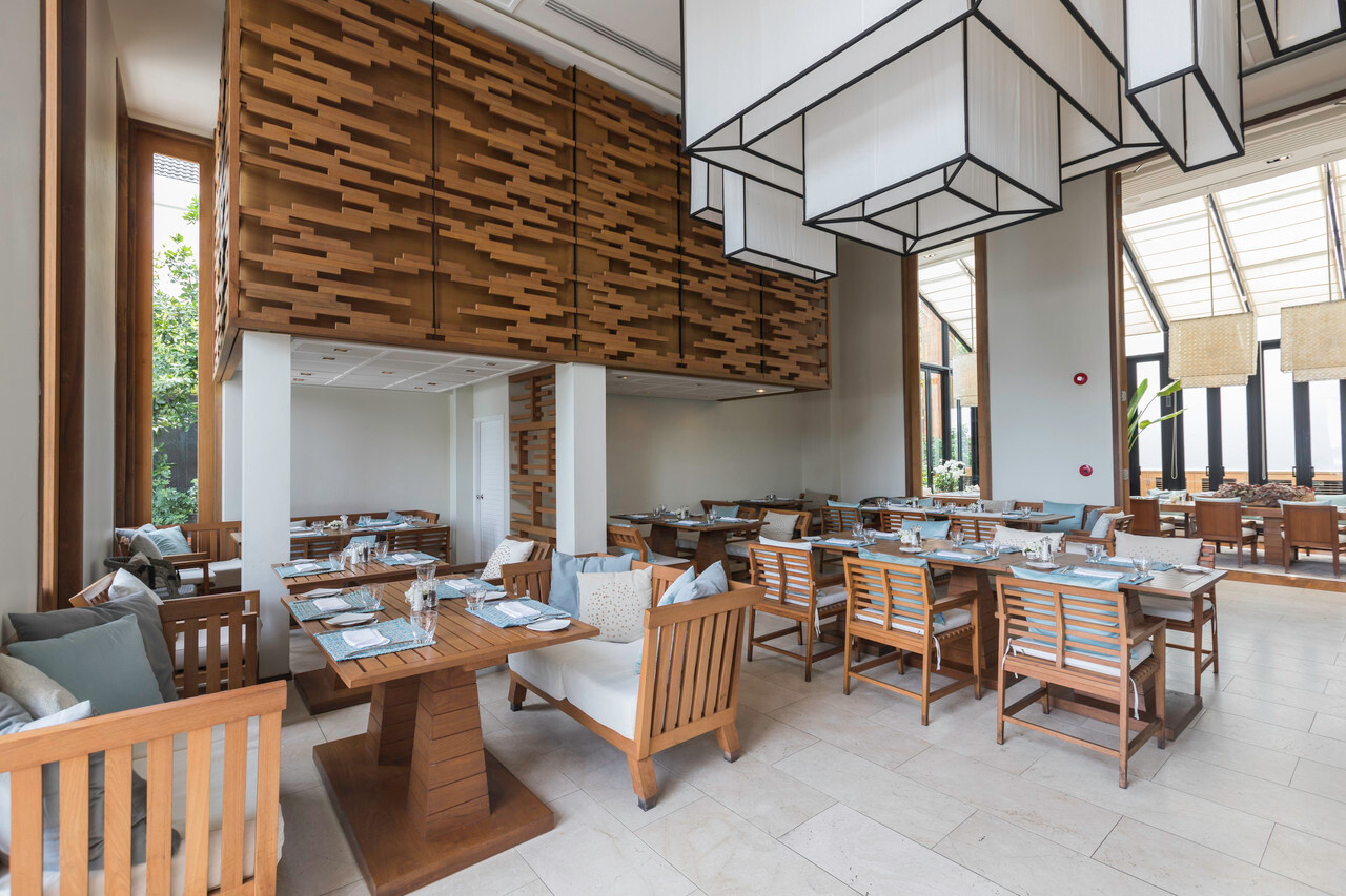 Rocks restaurant with high ceilings and teak tables at Cape Nidhra