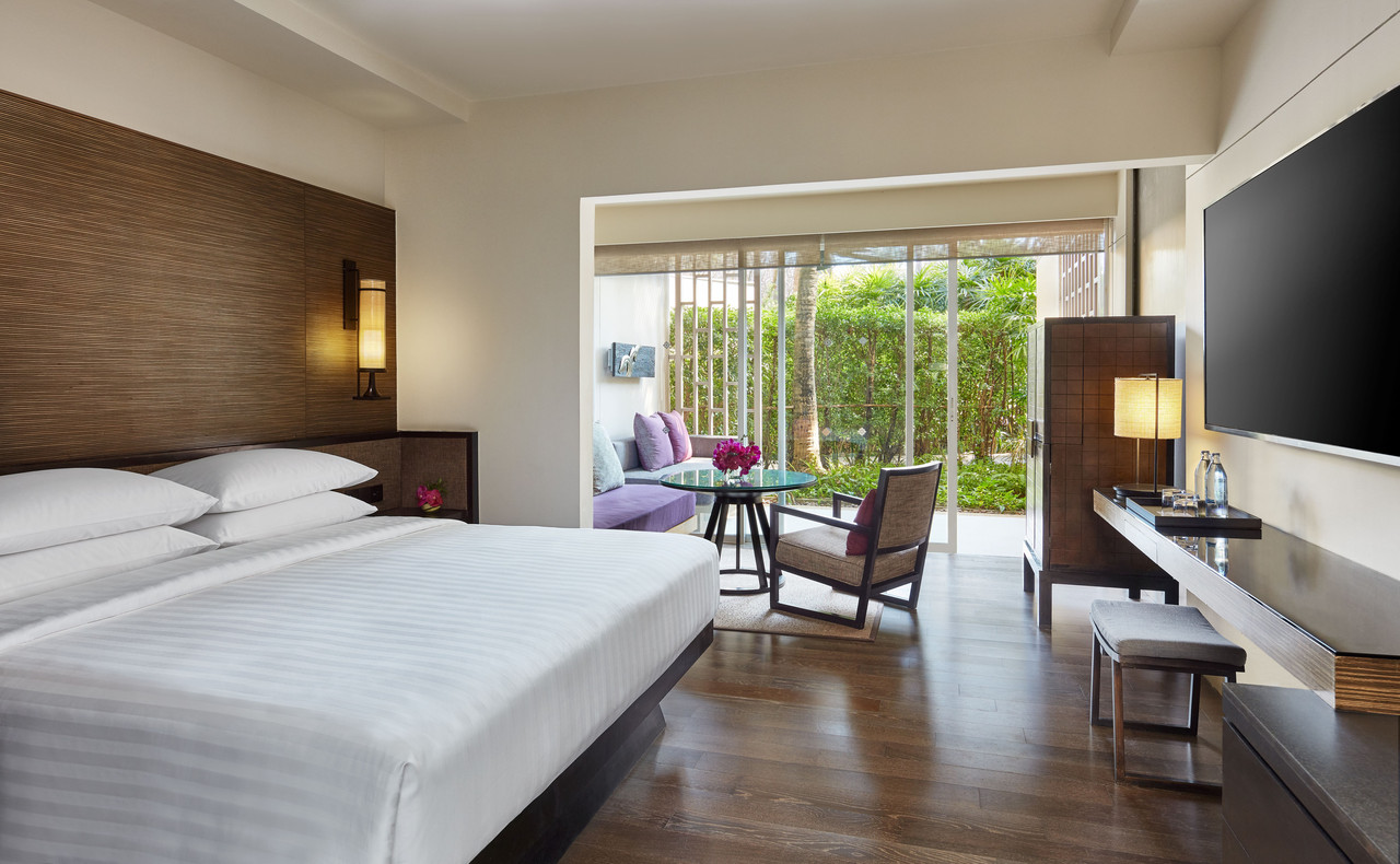 Bright wood-toned guest room with a daybed and garden view at Hyatt Regency Hua Hin
