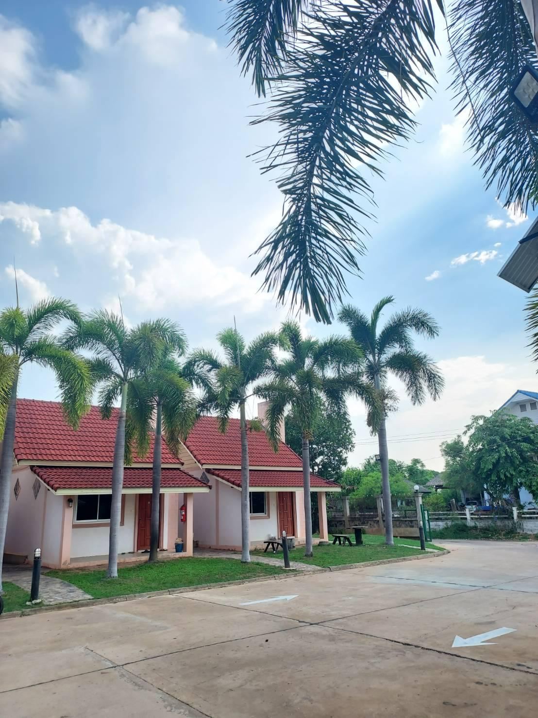 บ้านพักหลังเดี่ยวหลังคากระเบื้องแดงเรียงใต้ต้นปาล์ม กับลานจอดรถหน้าห้อง