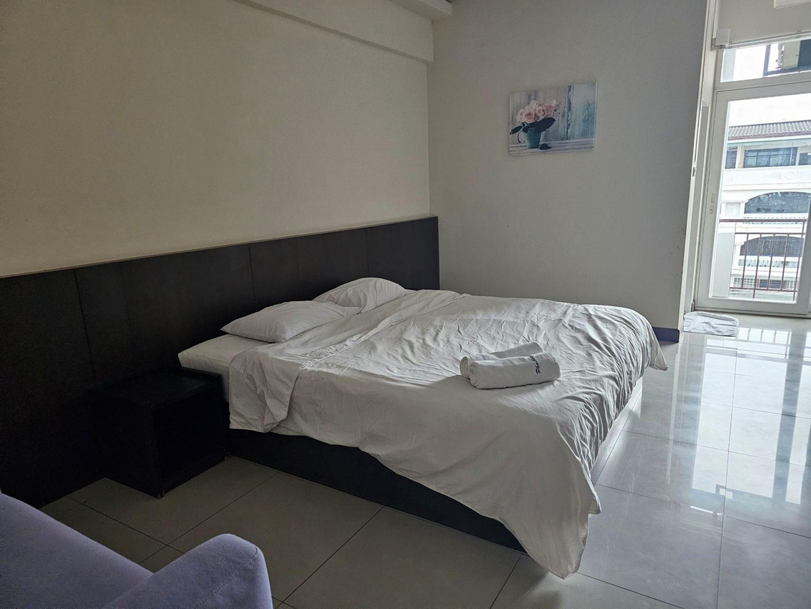 Phaiboon Place Hotel guest room with a large bed, clean tiled floor and a door to the balcony