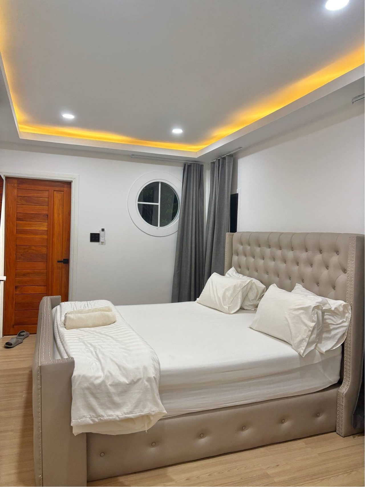 ห้องนอนเตียงคิงของ Romlaphass Boutique Villa หัวเตียงบุนวมโทนครีม ไฟซ่อนอุ่นๆ