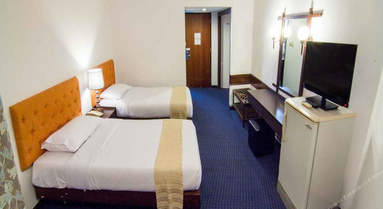 Twin-bed guest room at Phet Hotel Kamphaeng Phet with blue carpet and orange headboards