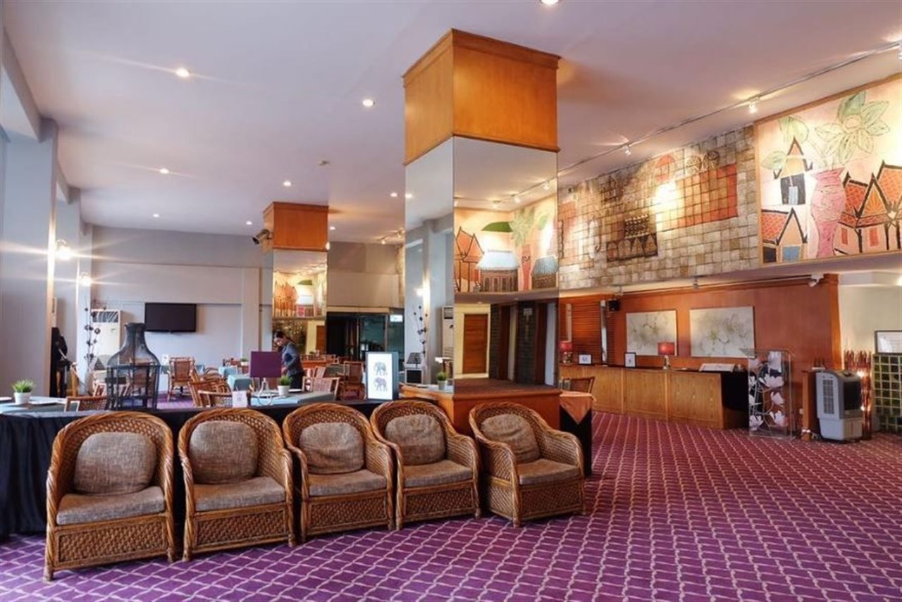 Spacious lobby with rattan armchairs and Thai mural artwork at Phet Hotel