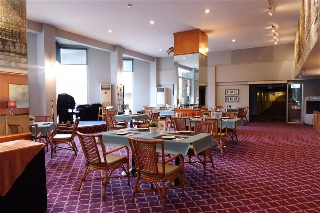On-site Thai restaurant with blue table linens and patterned carpet at Phet Hotel