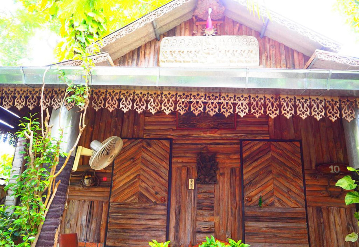 A small teak bungalow at Three J Guesthouse with carved fretwork under the eaves