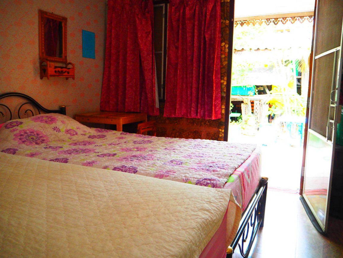 A twin room opening onto the green garden, with red curtains and a floral bedspread
