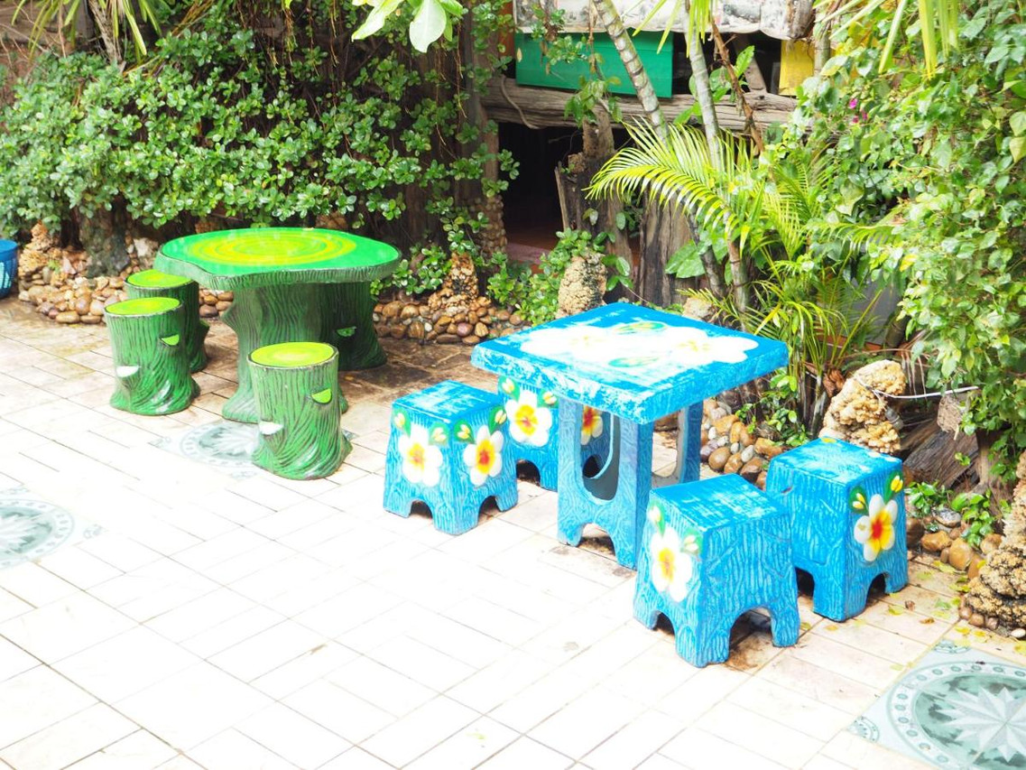 A garden corner of the guesthouse with hand-painted concrete tables and stools in green and blue floral patterns