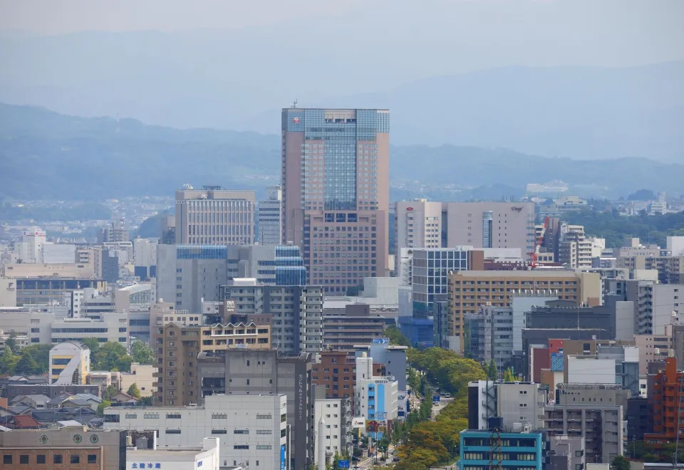 Hotel Nikko Kanazawa tower rising above the Kanazawa cityscape with mountains in the background