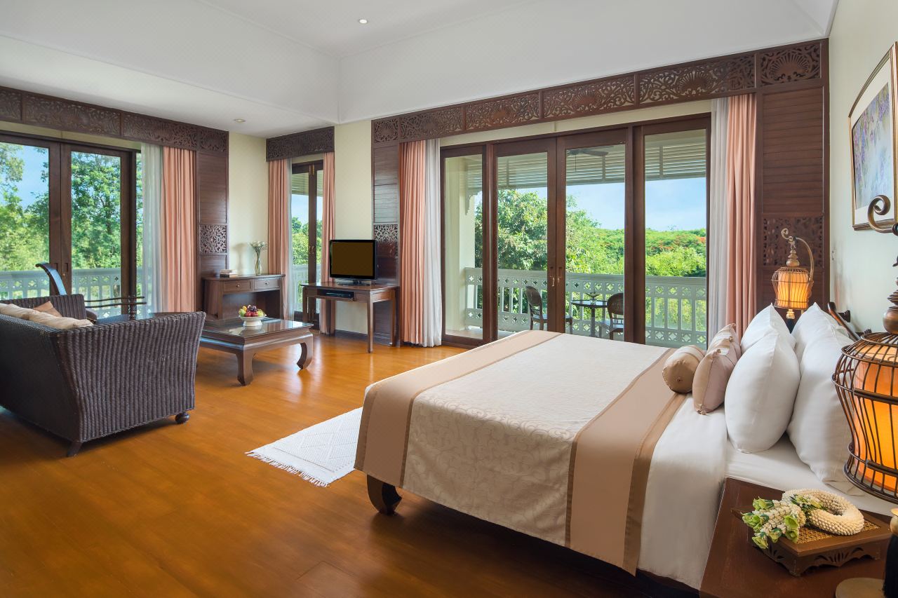 Guest room with teak floors, carved-wood bed and a garden-view balcony