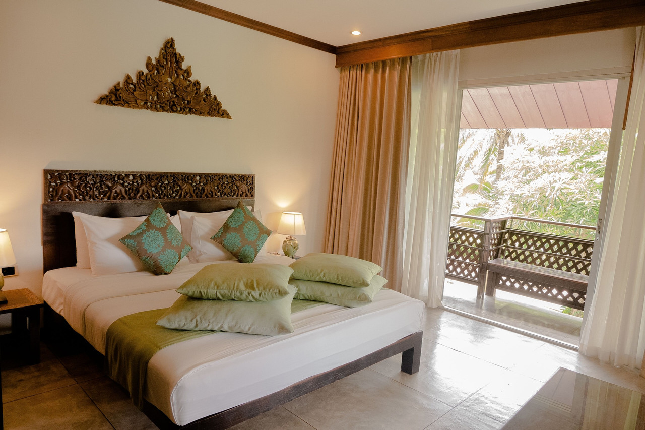 Guest room with carved teak headboard and private balcony