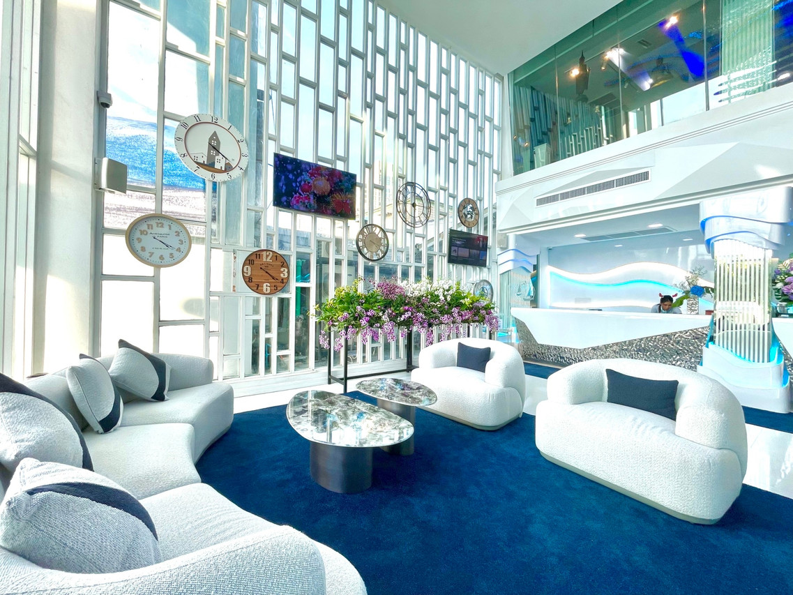 Glacier Hotel Khon Kaen lobby in blue tones with white sofas and a clock wall