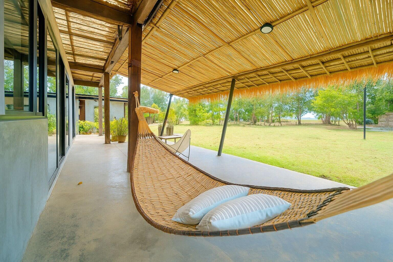 Cabana terrace with a woven hammock looking out over the garden toward the sea