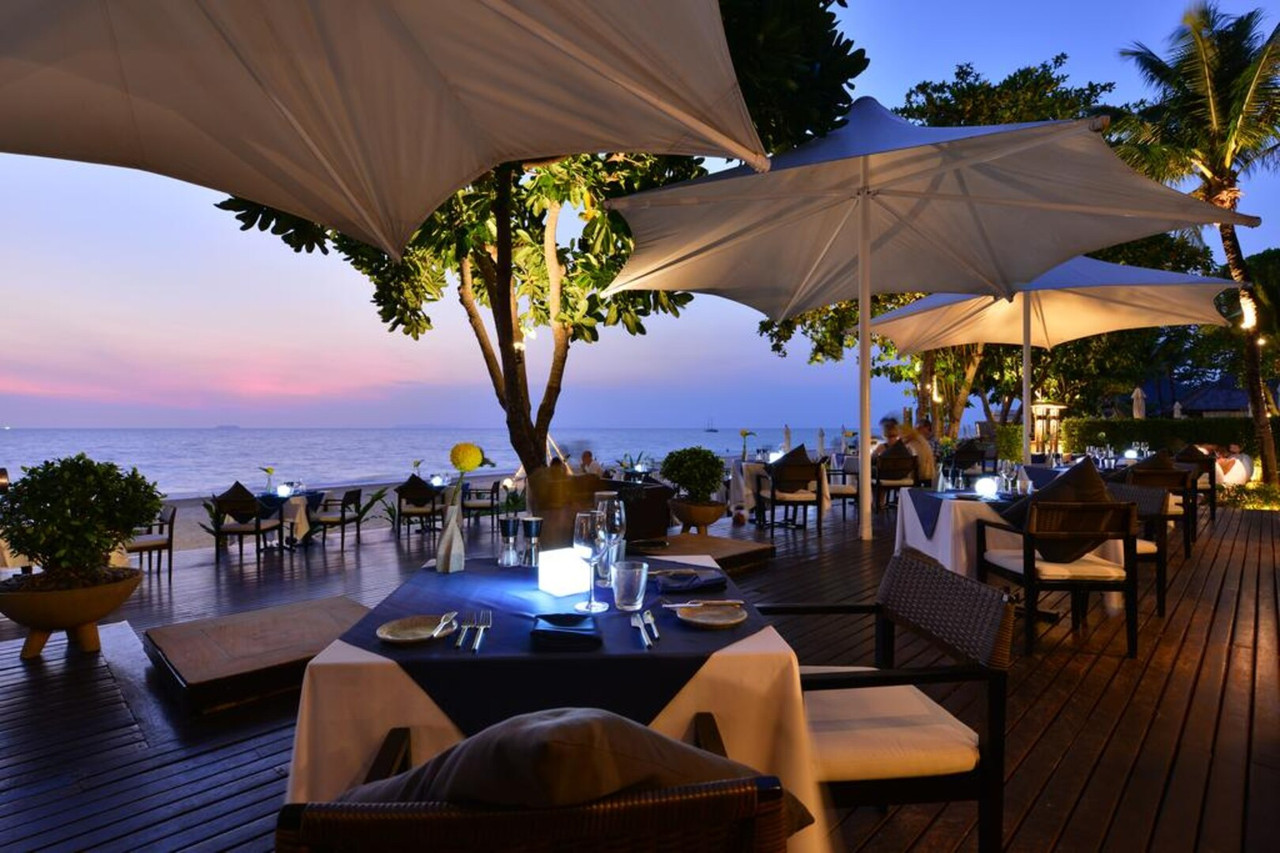 Beachfront SeaSky restaurant deck at sunset, tables by the sea with lamps