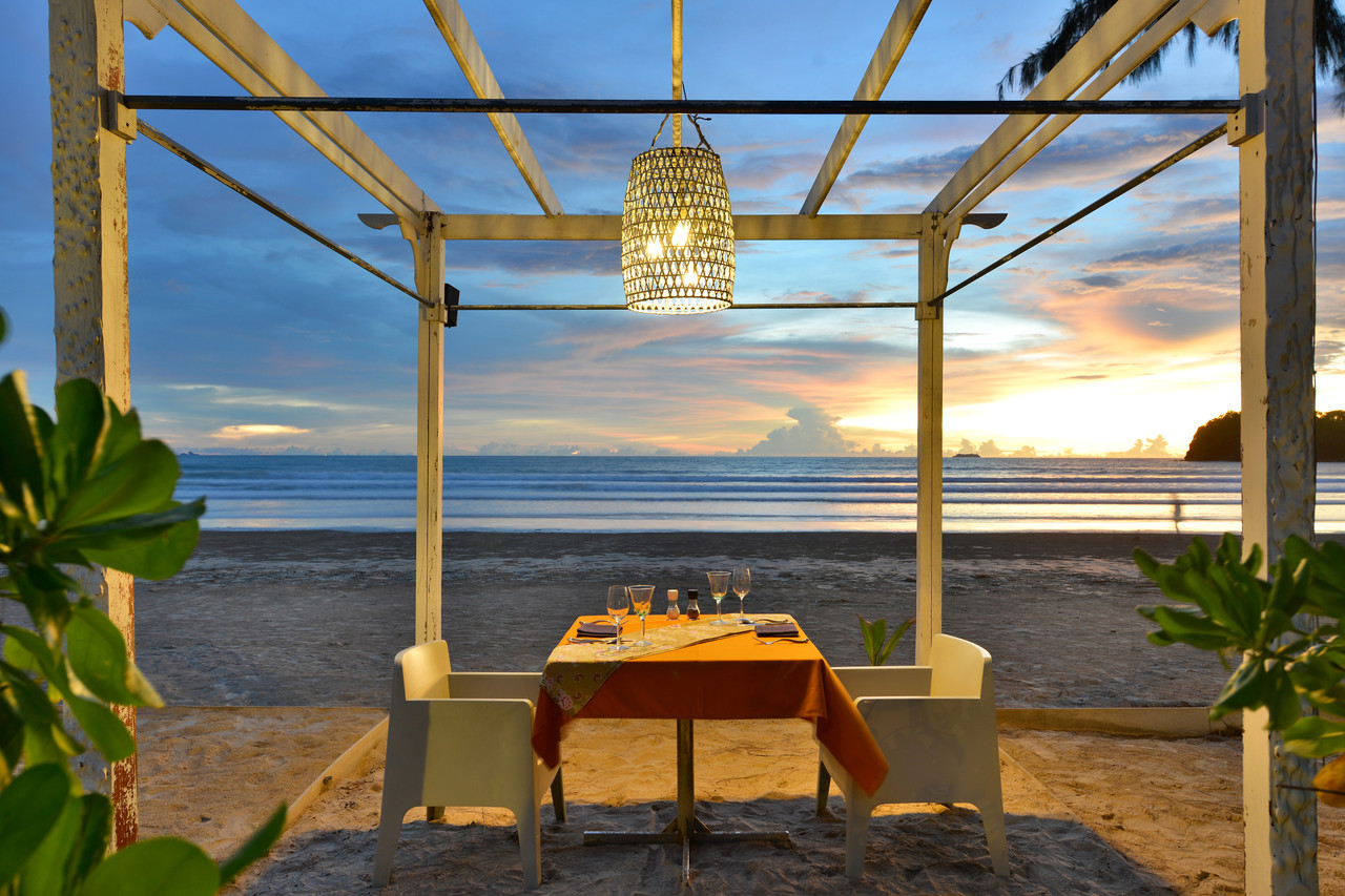Beachfront dining table on Klong Dao Beach at sunset over the Andaman Sea