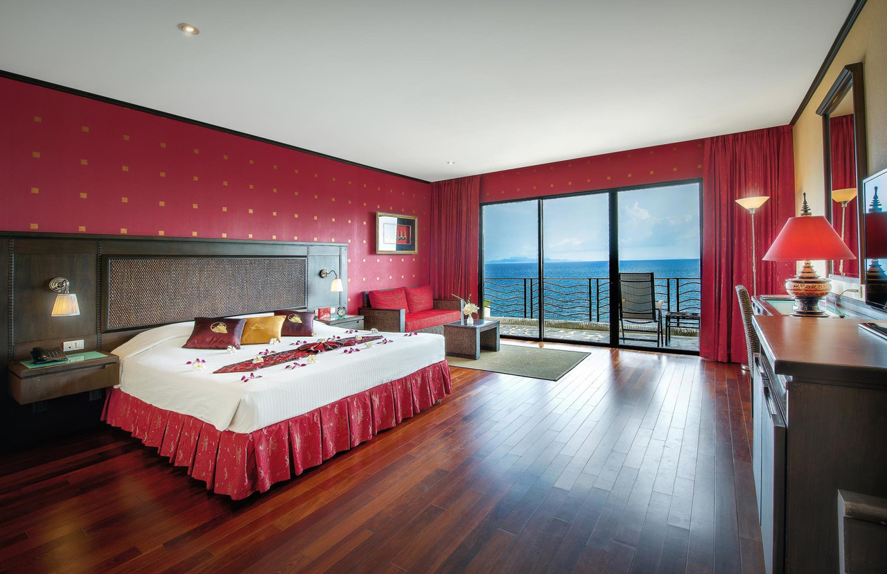ห้อง Deluxe Suite วิวทะเล ผนังสีแดง กระจกบานใหญ่เปิดออกระเบียงเหนือหน้าผา