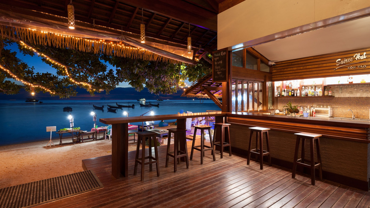 บาร์ริมทะเลของ Sairee Hut Resort ช่วงพลบค่ำ มีเรือหางยาวจอดริมหาดทรายรี