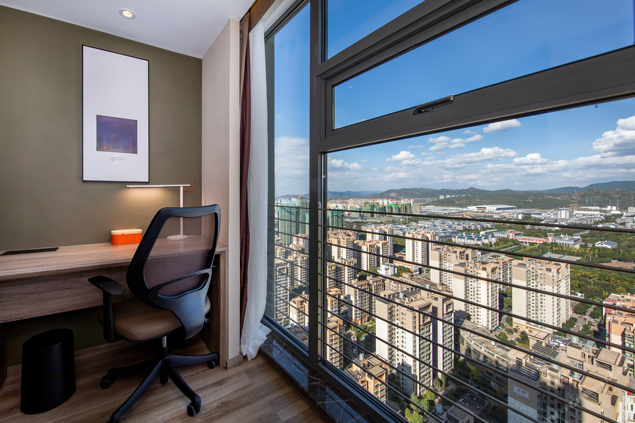 A guest room in the new Atour Kunming South building, with a sofa, vanity and a high-floor city view