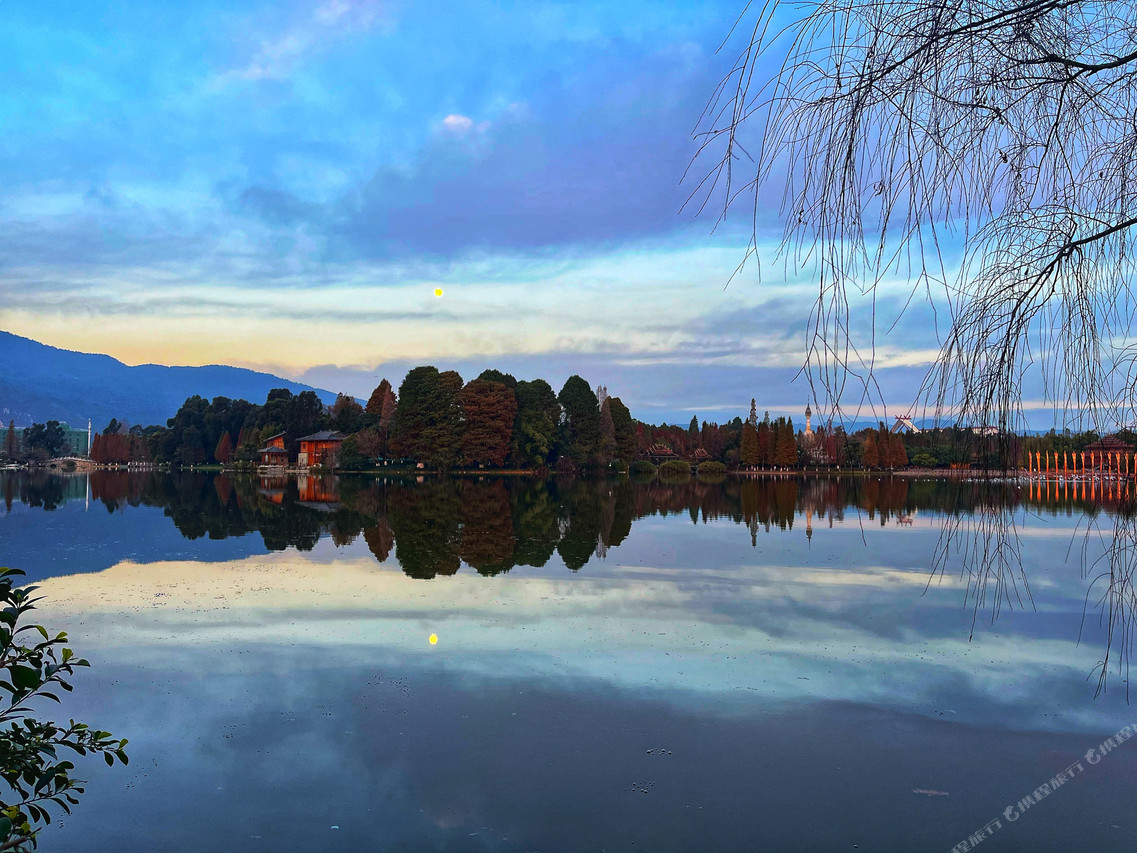Dianchi Garden Resort & Spa Kunming (昆明滇池花园酒店) — อาคารรีสอร์ตสีขาวท่ามกลางสวนต้นไม้ใหญ่ใต้ท้องฟ้าใส