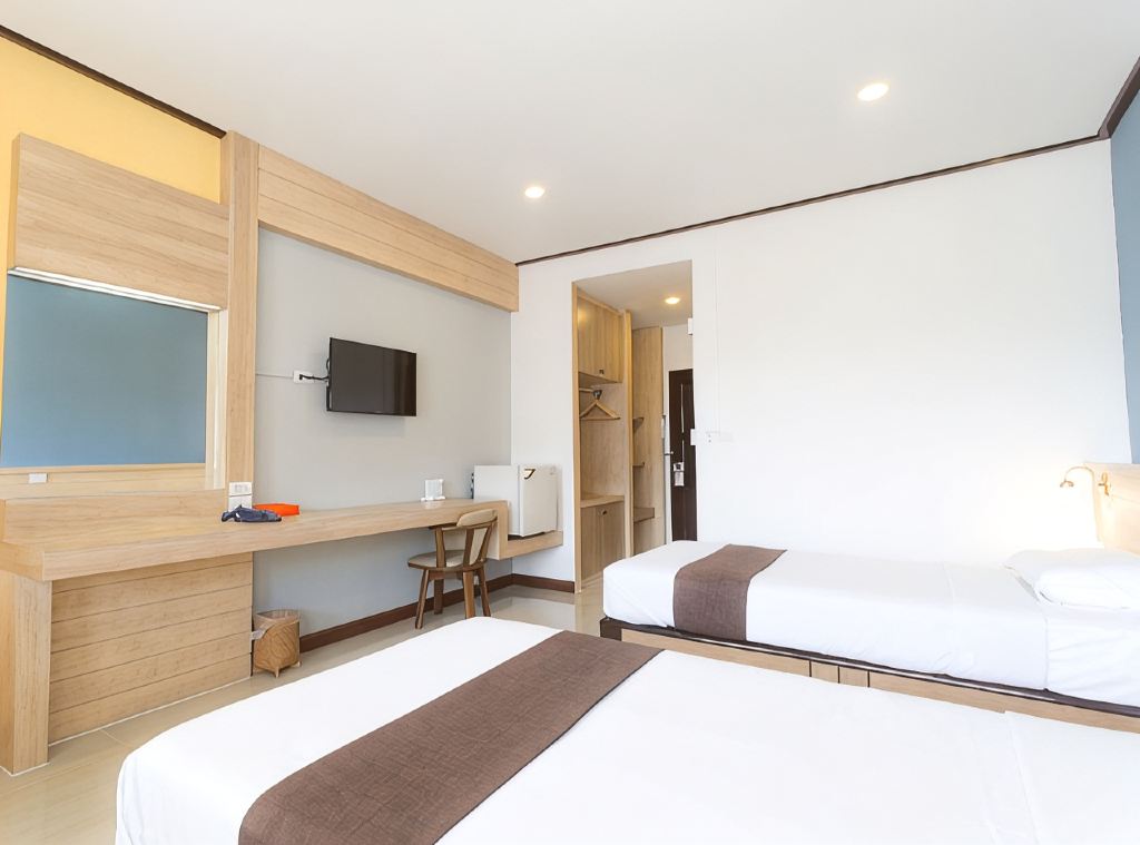 Twin guest room at Asia Lampang Hotel with light wood panelling and a long work desk