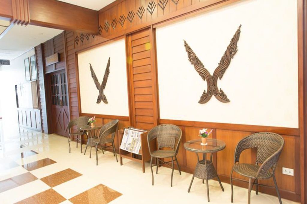 Teak-panelled lobby seating area with Lanna kanok motifs on the wall